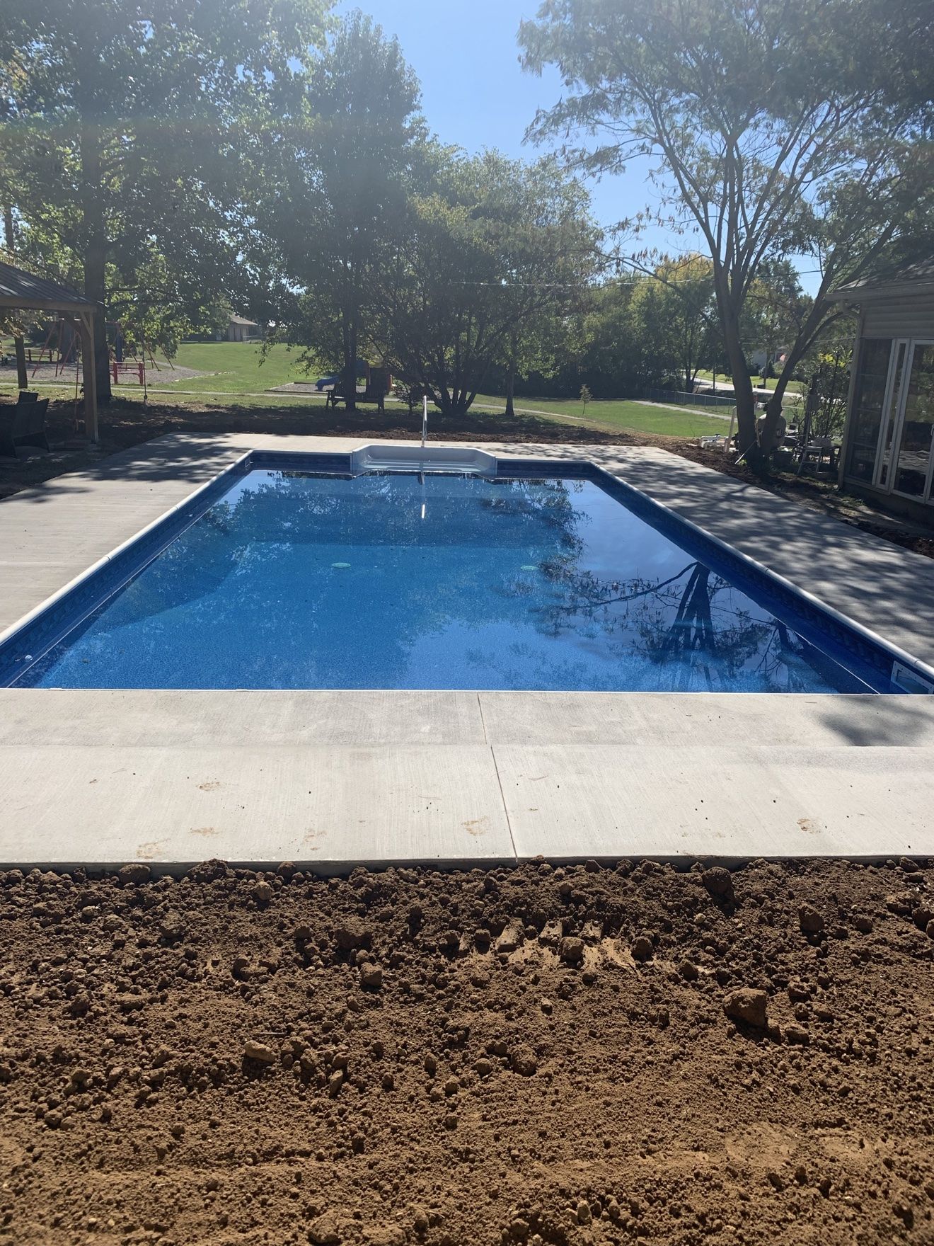New inground pool build with deep blue water and a fresh concrete deck